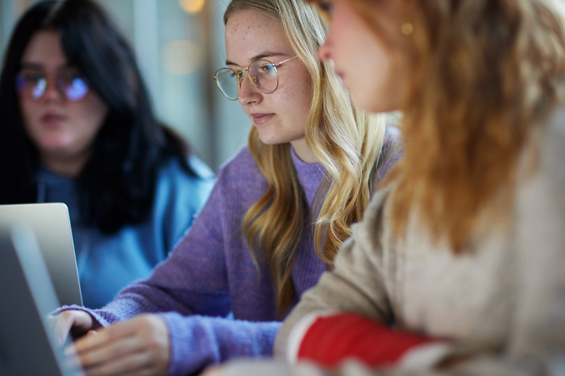 3 piger sidder og kigger på en computer
