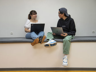 En ung pige og dreng snakker sammen siddende på en bænk